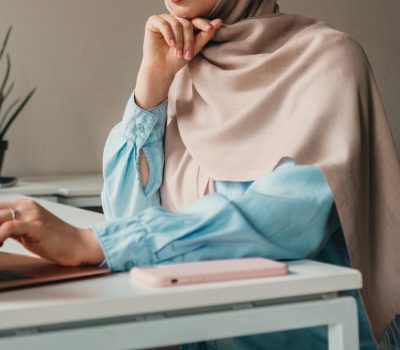 young pretty modern muslim woman in hijab working on laptop in office room, education online, remote work freelancer, typing thinking concentrated